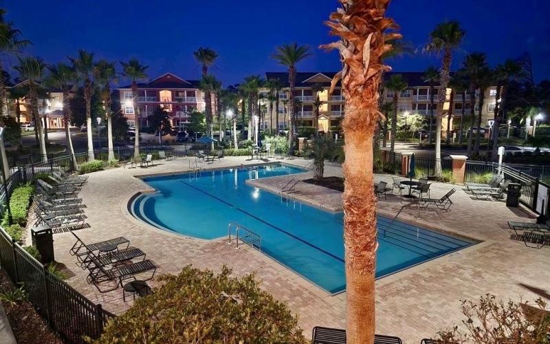 a pool with palm trees and buildings